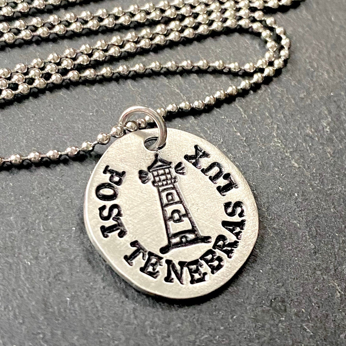 post tenebras lux Latin phrase necklace. After darkness, light. hand stamped pewter pendant with stamped lighthouse at the center. drake designs jewelry