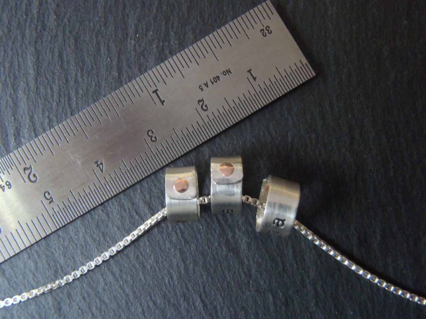 tiny sterling silver ring charms riveted with childrens names. drake designs jewelry