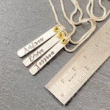 sterling silver mom necklace with kids names hand stamped in script font on thick vertical bar charms with gold accent. drake designs jewelry