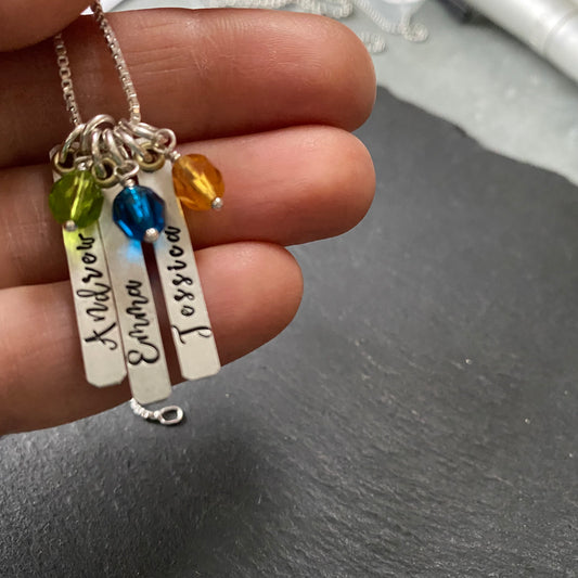 Thick Sterling silver charms with gold brass accent are hand stamped with kids names and birthstone charms are added. Drake designs jewelry