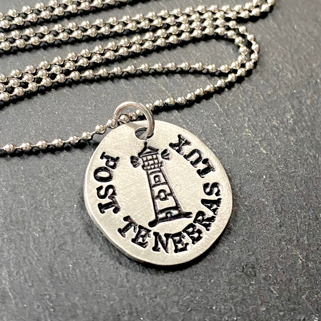 post tenebras lux Latin phrase necklace. After darkness, light.  hand stamped pewter pendant with stamped lighthouse at the center. drake designs jewelry