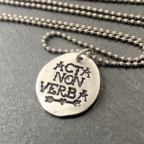 acta non verba latin phrase necklace.  deeds not words hand stamped in tattoo font in pewter disc with heart arrow. drake designs jewelry